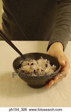 Mid section view of a woman holding a bowl of rice View Large Photo Image Stock Photograph - Mid section view of a woman holding a bowl of rice. Fotosearch