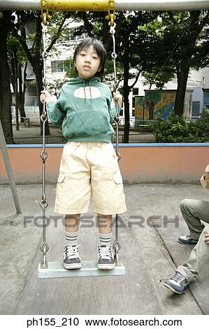 Portrait of a boy standing on a swing View Large Photo Image Stock Image - Portrait of a boy standing on a swing. Fotosearch