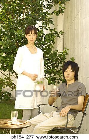 Portrait of a young man holding a glass of water with a young woman standing beside him View Large Photo Image Stock Photo - Portrait of a young man holding a glass of water with a young woman standing beside him. Fotosearch