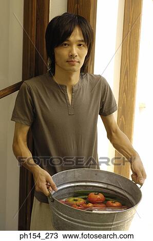 Portrait of a young man holding a washtub with vegetables View Large Photo Image Stock Image - Portrait of a young man holding a washtub with vegetables. Fotosearch