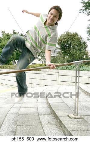 Stock Image - Portrait of a young man jumping over a railing. Fotosearch