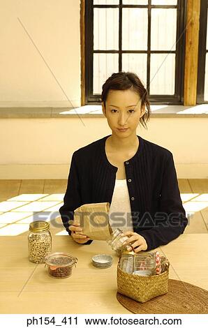 Portrait of a young woman filling a jar with beans View Large Photo Image Stock Image - Portrait of a young woman filling a jar with beans. Fotosearch