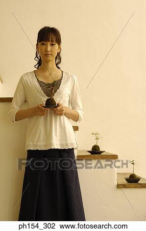 Portrait of a young woman holding a potted plant View Large Photo Image Stock Image - Portrait of a young woman holding a potted plant. Fotosearch