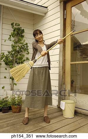 Portrait of a young woman holding a broom and smiling View Large Photo Image Stock Image - Portrait of a young woman holding a broom and smiling. Fotosearch