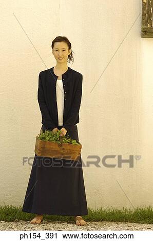 Portrait of a young woman holding a potted plant and smiling View Large Photo Image Stock Image - Portrait of a young woman holding a potted plant and smiling. Fotosearch