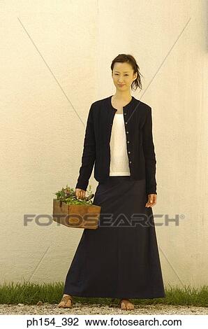 Portrait of a young woman holding a potted plant View Large Photo Image Stock Image - Portrait of a young woman holding a potted plant. Fotosearch