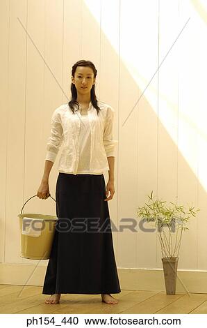 Portrait of a young woman holding a bucket View Large Photo Image Stock Image - Portrait of a young woman holding a bucket. Fotosearch
