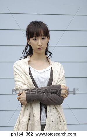 Stock Image - Portrait of a young woman standing with her arms crossed. Fotosearch