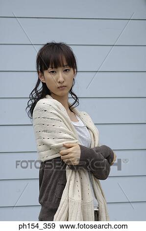 Stock Photo - Portrait of a young woman standing with her arms crossed. Fotosearch