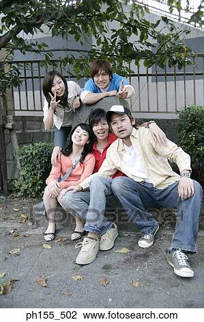Stock Image - Portrait of three young men and two young women posing. Fotosearch
