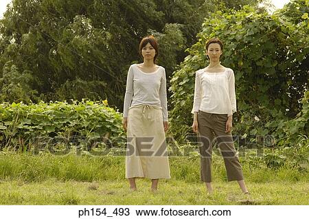 Portrait of two young women standing in a field View Large Photo Image Stock Image - Portrait of two young women standing in a field. Fotosearch