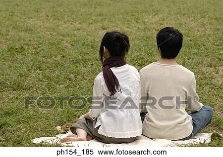 Rear view of a couple sitting together on a mat View Large Photo Image Stock Photography - Rear view of a couple sitting together on a mat. Fotosearch
