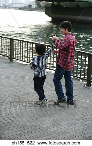 Rear view of a father walking with his son View Large Photo Image Stock Image - Rear view of a father walking with his son. Fotosearch