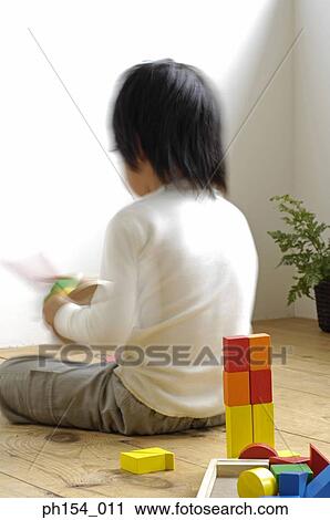 Stock Image - Rear view of a girl playing with toys. Fotosearch