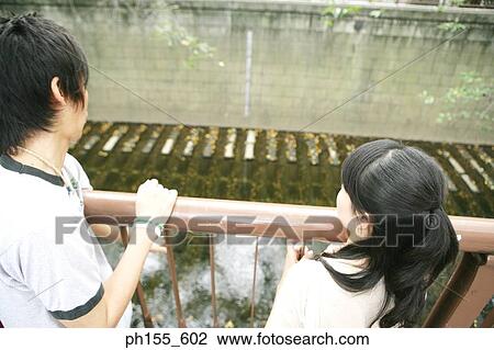 Rear view of a man and a woman bending forward on a railing View Large Photo Image Stock Image - Rear view of a man and a woman bending forward on a railing. Fotosearch
