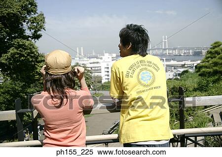 Rear view of a man and a woman standing against a railing View Large Photo Image Stock Photography - Rear view of a man and a woman standing against a railing. Fotosearch