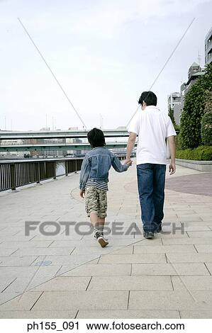 Rear view of a man and his son walking and holding hands View Large Photo Image Stock Image - Rear view of a man and his son walking and holding hands. Fotosearch