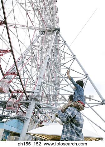 Rear view of a man carrying his child on his shoulders near a ferris wheel View Large Photo Image Stock Image - Rear view of a man carrying his child on his shoulders near a ferris wheel. Fotosearch