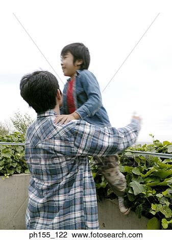 Rear view of a man carrying his son View Large Photo Image Stock Image - Rear view of a man carrying his son. Fotosearch