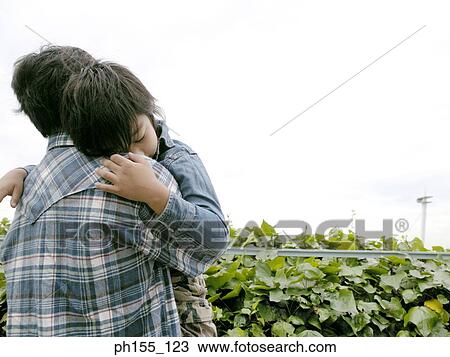 Stock Image - Rear view of a man carrying his son. Fotosearch