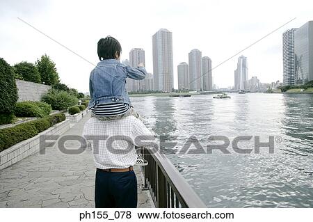 Rear view of a man carrying son on his shoulders View Large Photo Image Stock Photo - Rear view of a man carrying son on his shoulders. Fotosearch