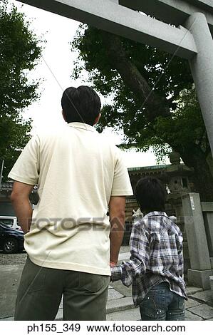 Stock Photo - Rear view of a mid adult man and his son at the entrance of a monastery. Fotosearch