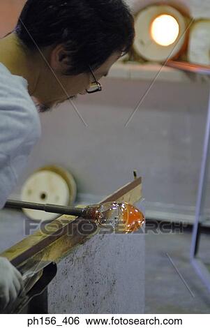 Stock Photograph - Rear view of a mid adult man molding a glass bulb. Fotosearch
