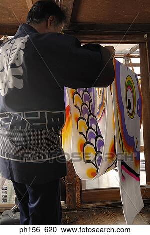 Stock Image - Rear view of a painter carrying painted sheets. Fotosearch
