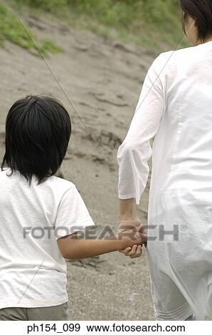 Stock Photo - Rear view of a woman and her son walking. Fotosearch