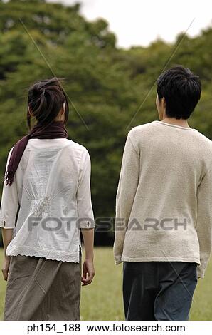 Rear view of a young couple standing together View Large Photo Image Stock Photo - Rear view of a young couple standing together. Fotosearch