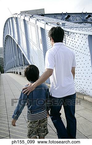 Rear view of a young man and his son walking on a bridge View Large Photo Image Stock Photo - Rear view of a young man and his son walking on a bridge. Fotosearch