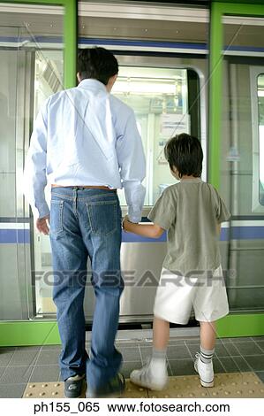 Rear view of a young man and his son standing at a subway station View Large Photo Image Stock Photography - Rear view of a young man and his son standing at a subway station. Fotosearch
