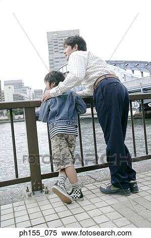 Rear view of a young man and his son standing near a railing View Large Photo Image Stock Photography - Rear view of a young man and his son standing near a railing. Fotosearch