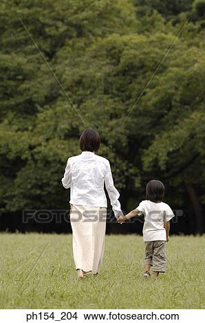 Rear view of a young woman walking with her daughter View Large Photo Image Picture - Rear view of a young woman walking with her daughter. Fotosearch