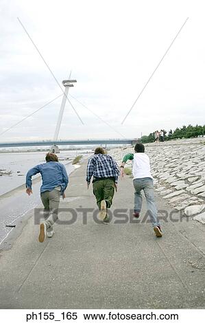 Rear view of three men running near a river View Large Photo Image Stock Photography - Rear view of three men running near a river. Fotosearch