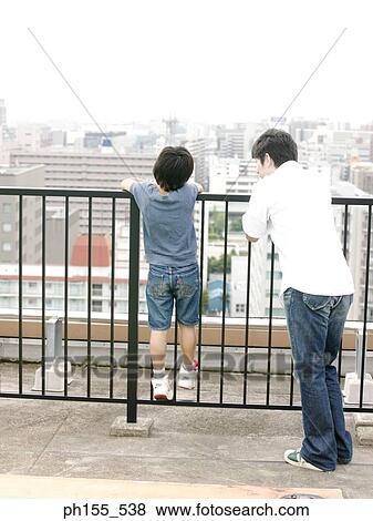 Rear view of two people holding a railing View Large Photo Image Stock Photo - Rear view of two people holding a railing. Fotosearch