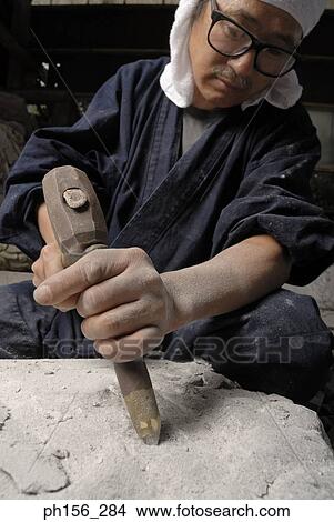 Picture - Sculptor carving a stone with a chisel and a hammer. Fotosearch