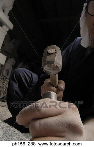 Stock Photo - Sculptor carving a stone with a chisel and a hammer. Fotosearch