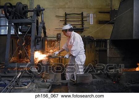 Stock Photo - Side profile of a blacksmith working in a workshop. Fotosearch