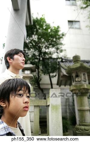 Stock Image - Side profile of a boy and his father at a monastery. Fotosearch