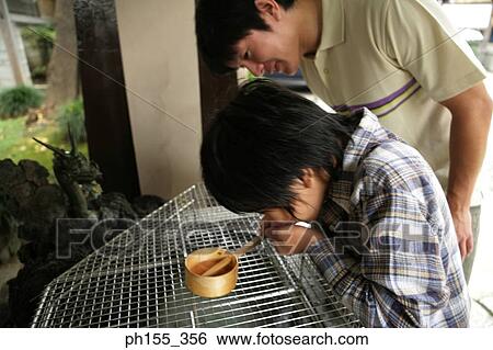 Stock Photograph - Side profile of a boy drinking water from a ladle. Fotosearch