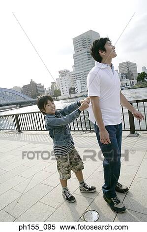 Stock Photography - Side profile of a boy pulling his father's polo shirt. Fotosearch