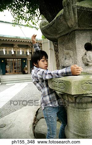 Stock Photo - Side profile of a boy standing near a birdhouse. Fotosearch