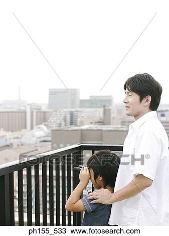 Side profile of a boy standing with his father and looking through a pair of binoculars View Large Photo Image Stock Image - Side profile of a boy standing with his father and looking through a pair of binoculars. Fotosearch