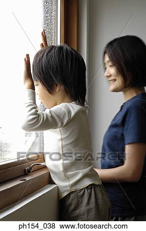 Stock Photo - Side profile of a girl and her mother looking through a window. Fotosearch