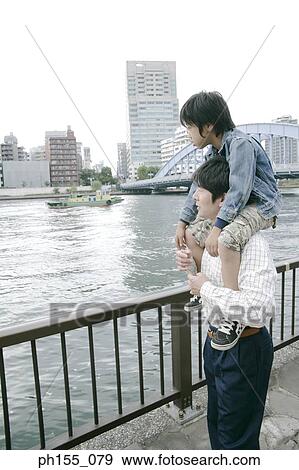 Side profile of a man carrying his son on his shoulders View Large Photo Image Stock Photo - Side profile of a man carrying his son on his shoulders. Fotosearch