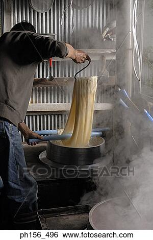 Stock Photograph - Side profile of a man dyeing silk threads in a workshop. Fotosearch