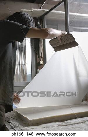 Stock Photograph - Side profile of a man holding a sheet of paper and a brush. Fotosearch