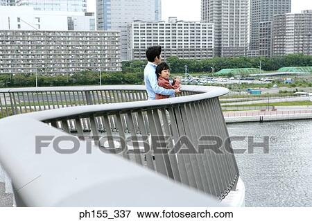Stock Photo - Side profile of a mid adult man holding his son from behind. Fotosearch