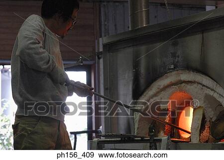 Stock Photo - Side profile of a mid adult man molding a glass bulb. Fotosearch